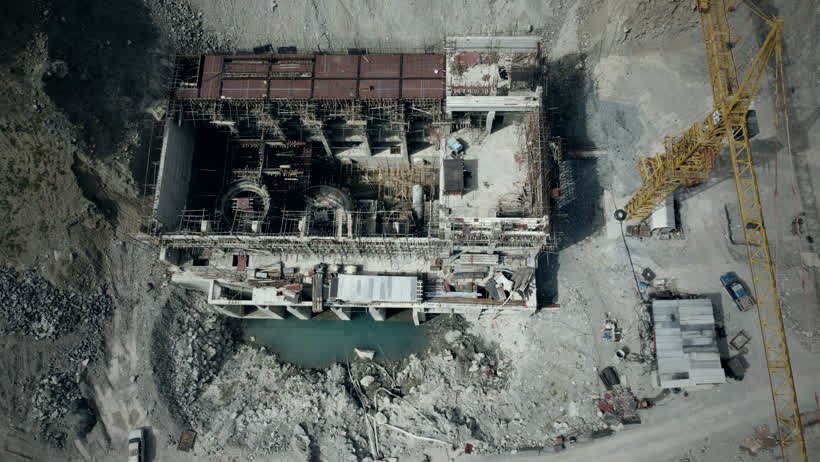 Vista aérea de um canteiro de obras com guindaste e estrutura de concreto